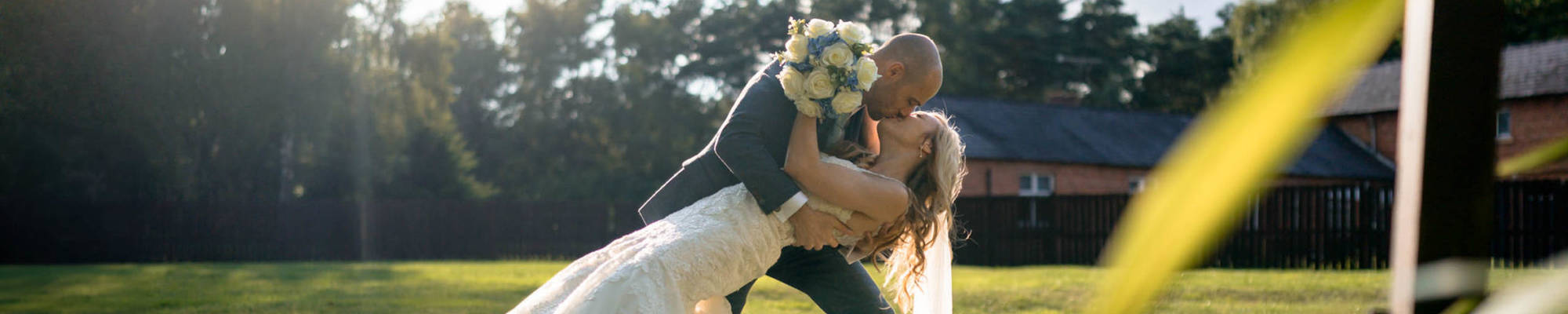 Couple kiss in warm golden sunset in the gardens of Nunsmere Hall Hotel
