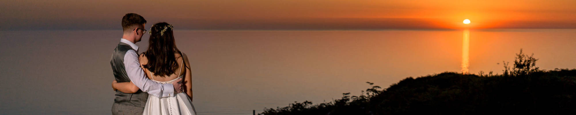 Newlyweds watching the sunset over the sea from the viewpoint above Nant Gwrtheyrn.